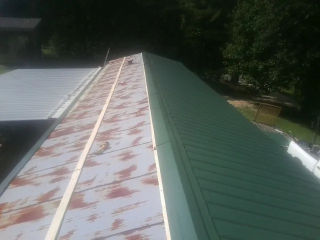 Old rusted panels beside newly installed green metal roofing — Wind Damage Roof Repair by Roofing Brothers in Loudon