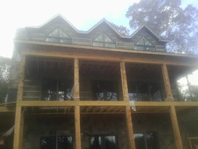 Dormers and porch framing on a large log home under construction — Roof Coating work by our crew in Loudon